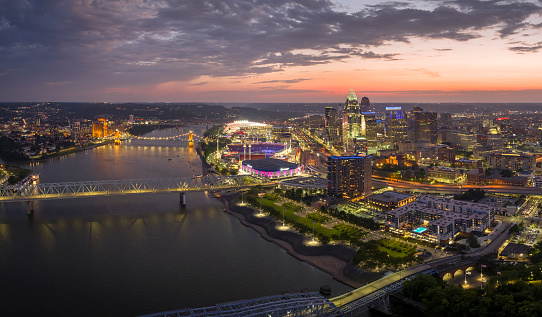 Aerial view of downtown district highway traffic in Cincinnati city, Ohio at night. Brightly illuminated high skyscraper buildings in modern American midtown.