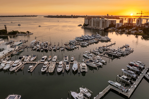 Sarasota Bay marina with luxury yachts and Florida city architecture at sunset. High-rise office buildings in downtown district. Real estate development in Florida. USA travel destination.