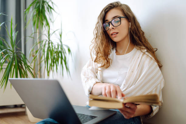 istock Young woman sits at home, learning preparing for exam using literature and laptop, 1963291078