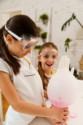Two girls having fun making experiments with baking soda and vinegar mixed with food colors