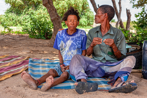 an old bushman san man from Central Kalahari, village New Xade in Botswana, in front of his yard sitting with the wife