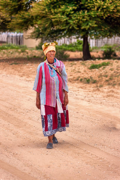 mujer africana anciana basarwa que camina por un camino de tierra en la aldea tradicional - khoikhoi woman fotografías e imágenes de stock