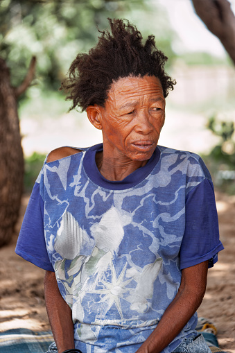 an old bushmen san woman from Central Kalahari, village New Xade in Botswana, in the yard of the home after relocation