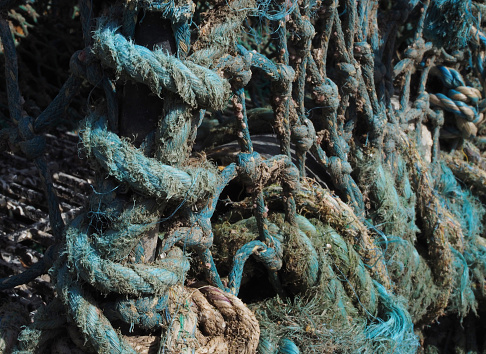 Close up of old encrusted turquoise fishing rope on quayside in fishing village