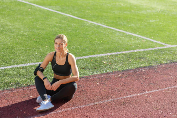 istock Active woman taking a break during outdoor workout on sunny track field 1963399361