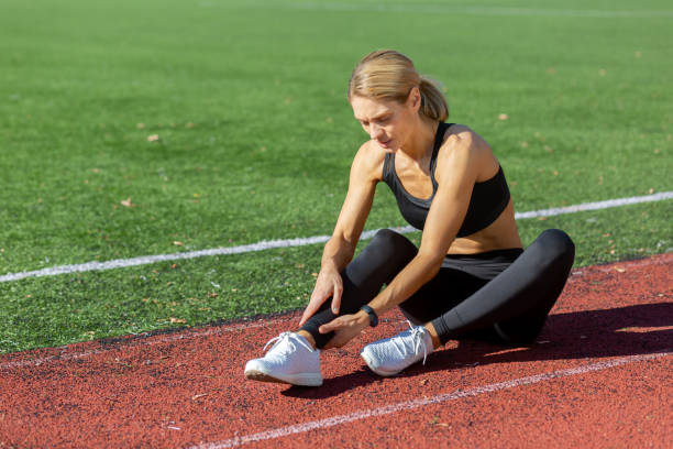 Female athlete experiencing a painful ankle injury while training on a running track