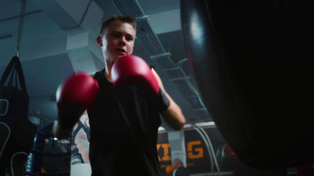 istock Confident young fighter hits punching bag while training in gym 1963430948