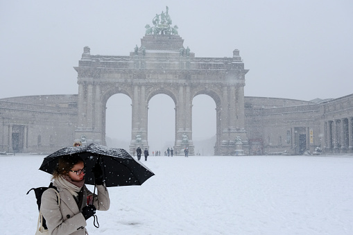 A woman holds an umbrella as she walk in central Brussels during a heavy snowfall in Belgium on January 17, 2024.