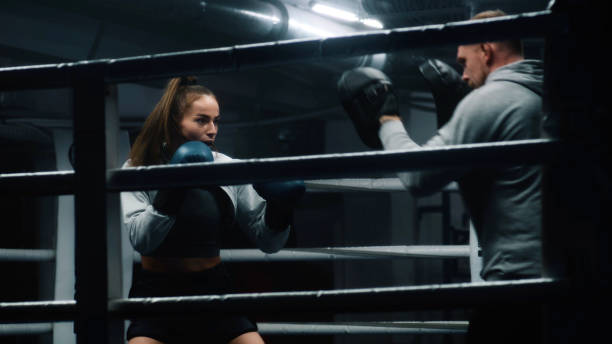 istock Athletic woman hits punching mitts on boxing ring 1963482622