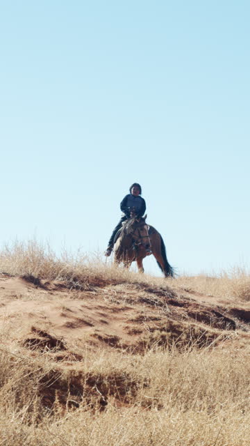 Vertical Video Young Navajo Boy Riding Horseback in the Desert Landscape of Monument Valley Tribal Park Navajo Country on a Sunny Day