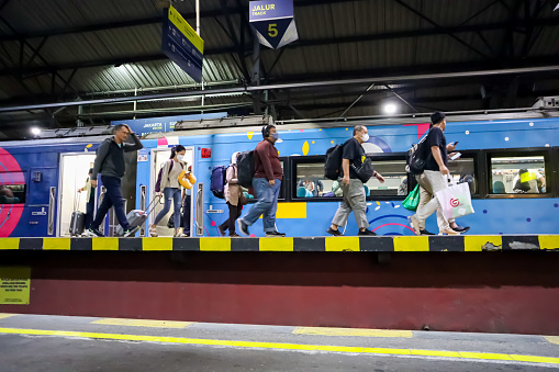 Crowd of passengers carrying bag and luggage walking on the platform with train stopped behind, holiday trip concept. Yogyakarta, Indonesia, December 23, 2023