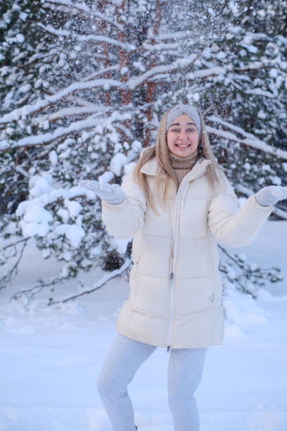 istock A woman in a white jacket and hat standing in the snow 1963523951