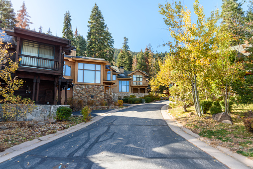 Modern houses along a street in a forested mountain setting on a sunny autumn day. Lake Tahoe, CA, USA.