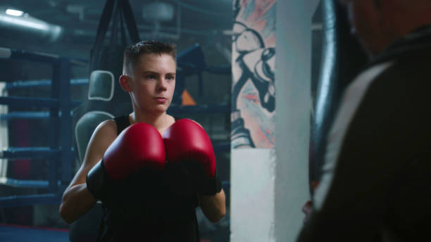 istock Confident young fighter hits punching bag while training in gym 1963555903