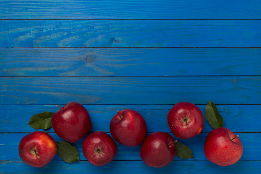 Fresh red apples with leaves on wooden background, top view