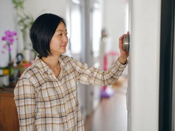 istock Woman Adjusting a Smart Thermostat in a Home 1963665257