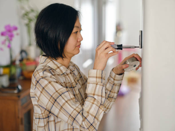 istock Woman Installing a Smart Thermostat in a Home 1963665806
