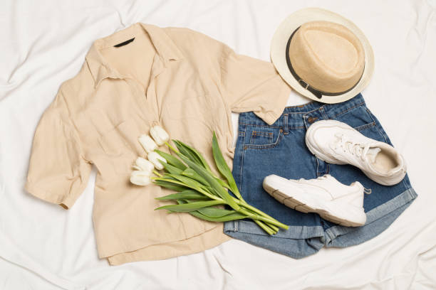 Stylish summer outfit on white sheet background, top view
