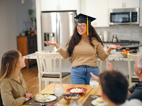A family having dinner together to celebrate an adult graduate in a home.