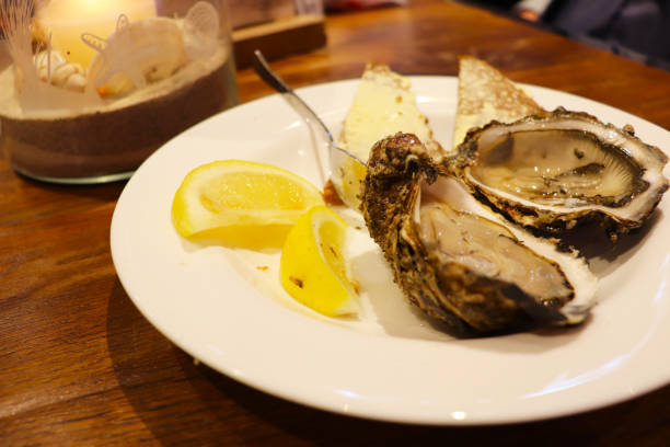 istock fresh oysters with lemon on a white plate and bread and butter 1963707398
