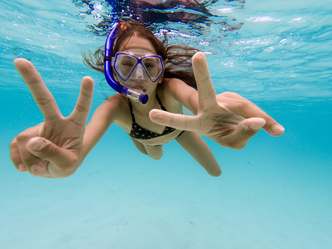 Happy Teen girl enjoying snorkelling and gesturing