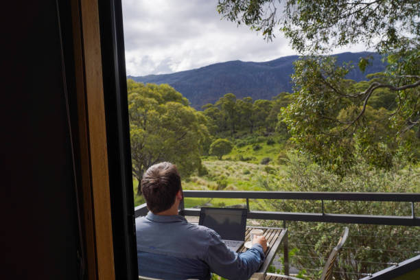 istock Male working remotely from his balcony looking over the mountains 1963793576