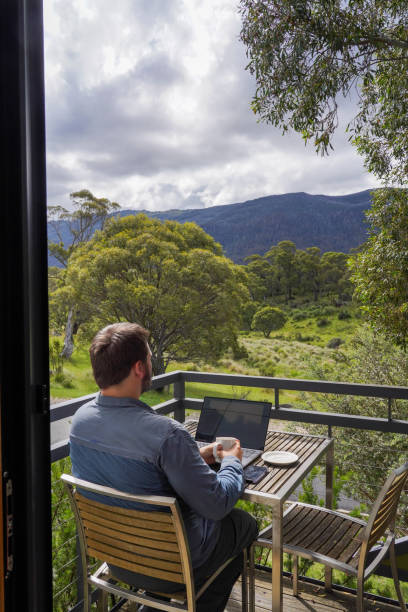 istock Male working remotely from his balcony looking over the mountains 1963794624