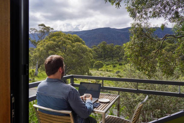 istock Male working remotely from his balcony looking over the mountains 1963794625