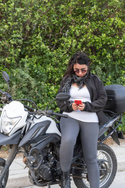 istock Young Woman on a motorcycle focused on her smartphone. 1963796172