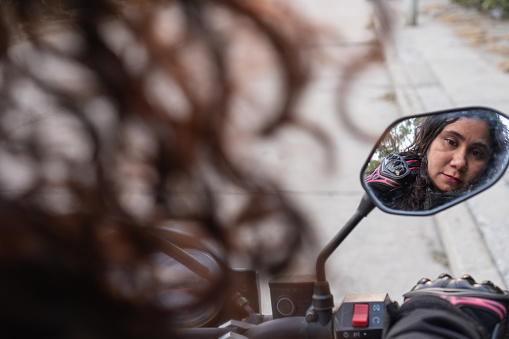 Introspective moment captured in the rearview mirror of a motorcyclist before a ride.