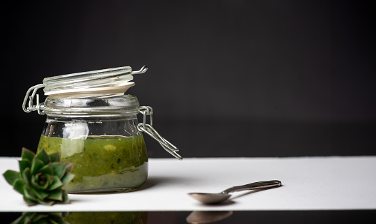 Natural, effective medicine from fresh leaves of sempervivum tectorum or common houseleek and honey in a glass jar on dark background.Tincture is suitable for treating many health problems