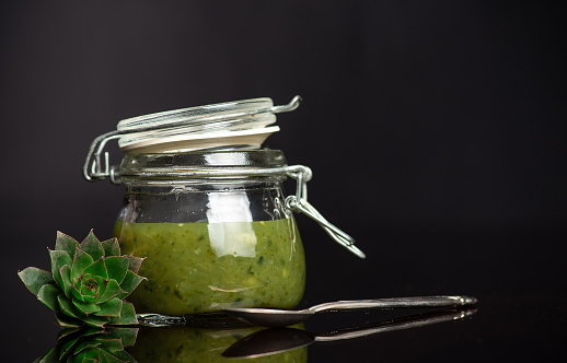 Natural, effective medicine from fresh leaves of sempervivum tectorum or common houseleek and honey in a glass jar on dark background.Tincture is suitable for treating many health problems
