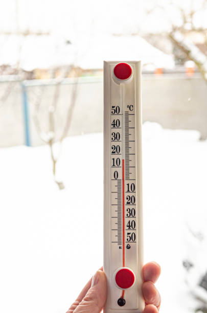 istock White thermometer with red scale in hand on window background. 1963888812