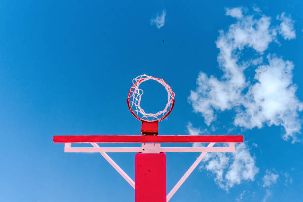 Basketball hoop over the blue sky and sport light pole.
