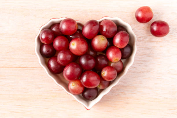 rote trauben in einer herzförmigen schale - grape heart shape fruit bunch stock-fotos und bilder