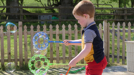 A child having fun with Soap Bubbles in the garden in summer