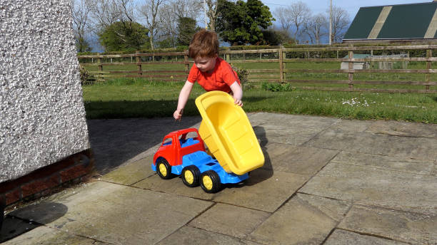 istock Red headed boy having fun playing with his toys in a garden 1963974326