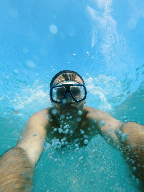 istock Swimmer in goggles dives under the water, raising splashes 1963994243