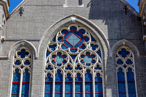 A decorative 19th century stained glass panel standing on the windowsill of St Mary’s church in Sedgeford, Norfolk, Eastern England. In Latin, it refers to the Holy Trinity - Father, Son and Holy Spirit - and explains that God is Father, Son and Holy Spirit.