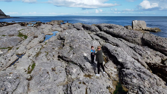 Aerial photo of Woman and child standing Rocks Mountains and Sea on Beautiful Scenery in the North Coast of Ireland