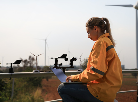 Female engineer with measurement instrument wind speed  working at wind turbine