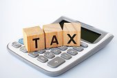 Tax wordings on wooden cubes on white cover background with calculator background. Taxation concept