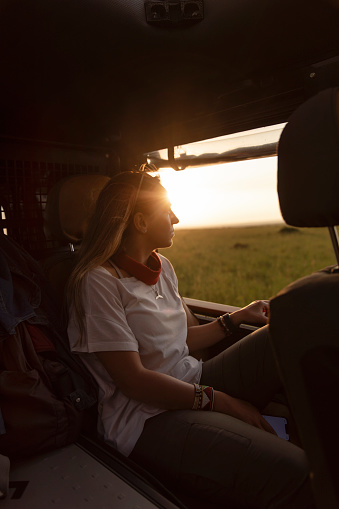 A young woman enjoying a safari ride in an SUV at sunset
