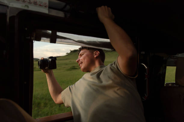 Photographer sticking out of the SUV to capture the best possible photo on safari