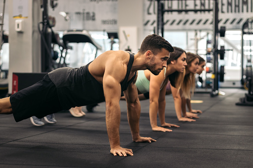 group of young people doing push ups in a gym