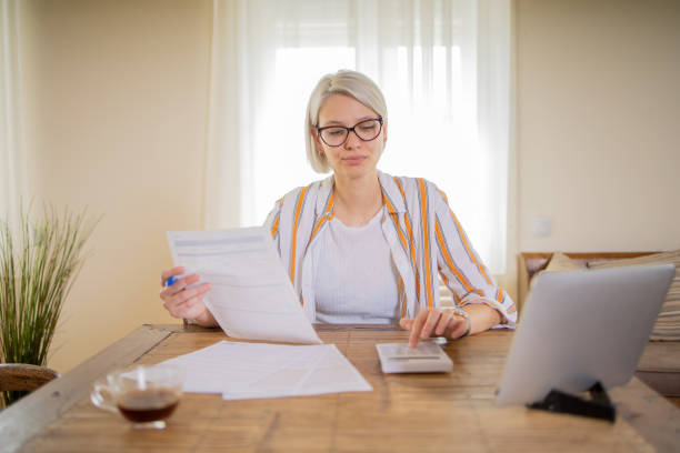 istock Young woman using calculator while going through bills and home finances 1964190152
