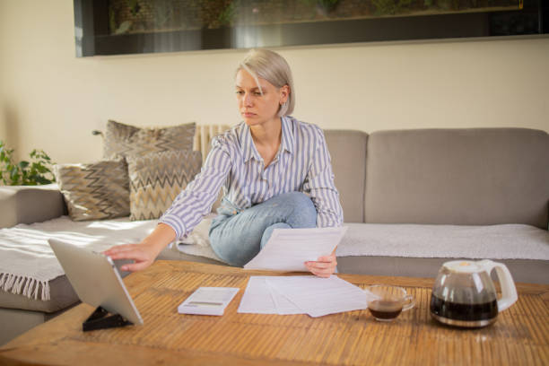istock Young woman using calculator while going through bills and home finances 1964190167
