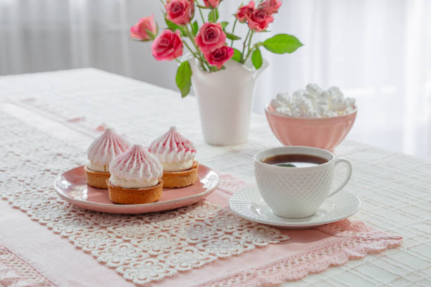 cup of coffee with dessert and roses on table