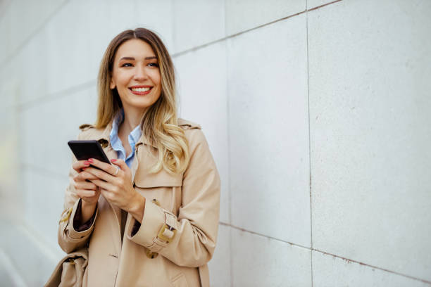 istock Woman using phone while standing next to a wall on city street. 1964202285