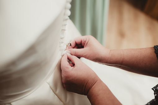 Mother using safety pin to help button her dress